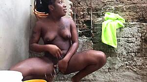 black bahian woman bathes with bucket in backyard