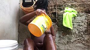 black bahian woman bathes with bucket in backyard