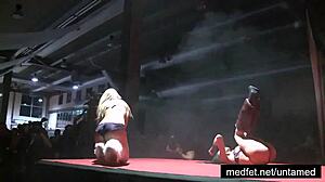 Two erotic girls perform a seductive striptease on stage, clothes ripping off