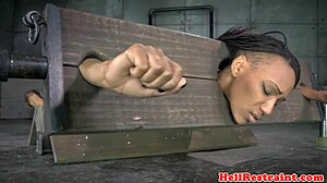 Bound ebony sub in pillory gets spanked