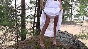 Lepa rjavolaska Lucy pokaže majhne sise in pičko v beli obleki v gozdu