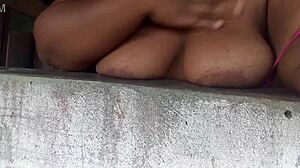 This naughty believer is showing her big tits to guys on the street from the window