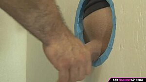 Trans na gloryholeu prima kurac kroz rupu